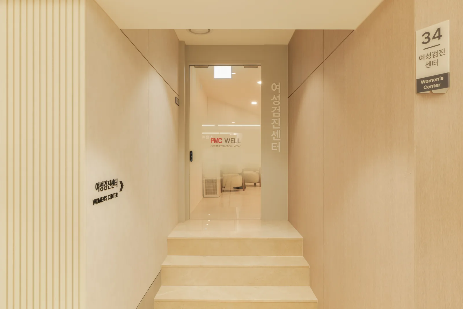 PMC 웰 센터 B1F 메인 통로에서 본 여성센터 입구 — '여성검진센터 34' 사인과 계단 위 유리문